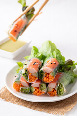 Salad roll with crab stick, carrot, cucumber and lettuce wrapped with rice paper on dish eating with dipping sauce