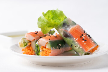 Salad roll with crab stick, carrot, cucumber and lettuce wrapped with rice paper on dish and dipping sauce