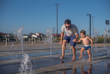Father helping his son overcome fear of the splash pad © MMV