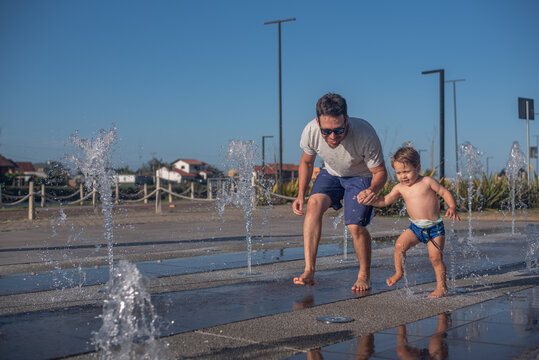 Father helping his son overcome fear of the splash pad
