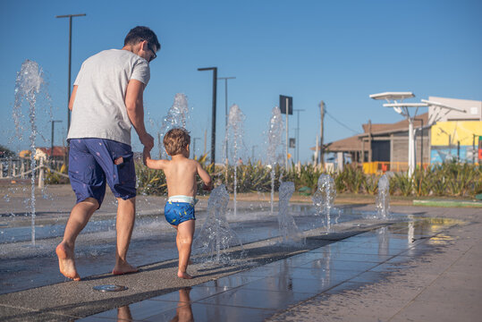 Father helping his son overcome fear of the splash pad