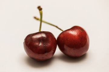 Two red ripe cherries on white background