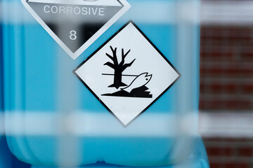 Hazard sign with dead fish and tree on blue container
