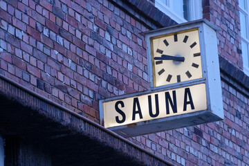Obraz premium Red Brick Building with Clock and Sauna Sign
