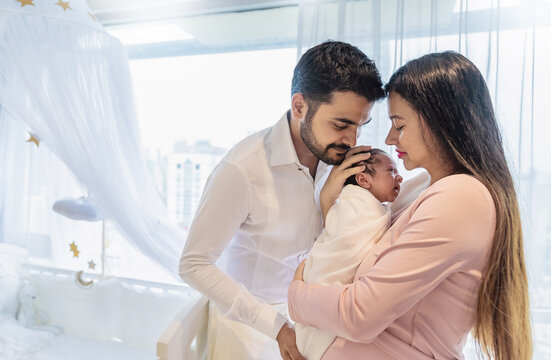 Portrait of Asian parents newborn baby day, Closeup of asian young couple father mother holding new born baby in hospital bed. Happy asia lovely family, nursery home breastfeeding mother’s day