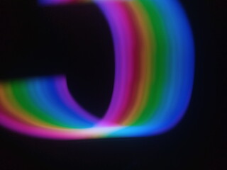 A multicolored abstract by moving strokes of light, creating bright, swirling streaks of rainbow-colored light on a dark background