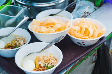 Chicken porridge. A mixture of rice, boiled egg, soybeans, shredded chicken, cracker, and vegetables, typical Indonesian food served as breakfast.