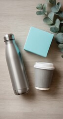 Silver water bottle, teal box, and grey coffee cup on light wood