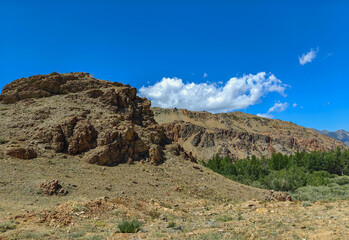 A stunning landscape of mountains and hills under a vibrant blue sky with clouds.