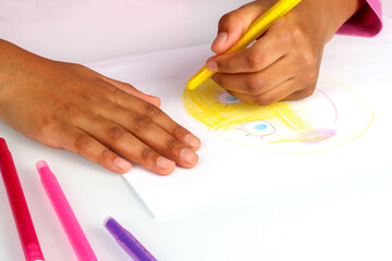 Child coloring a cheerful character with bright markers on white paper