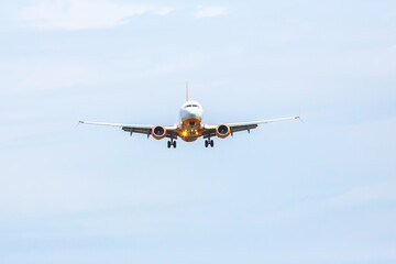 Airplane approaches landing at a cloudy airport, preparing for touchdown on the runway