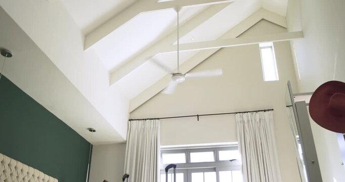 Camera tilting downward, revealing spinning fan and two suitcases standing waiting for travel