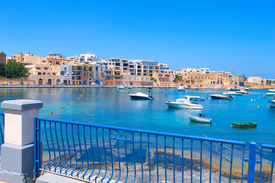 BIRZEBBUGA, MALTA - May 25, 2023: the Colorful small fishing boats moored with buoys in St George's Bay, in Birzebbuga, Malta