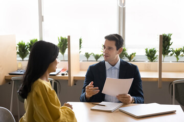 Multiethnic colleagues engaged in paperwork, share point, review contract details, preparing legal document for upcoming negotiations. Lawyer explaining agreement terms, provide consultation to client