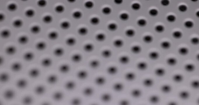 grate with lots of round holes, plastic surface with holes for ventilation