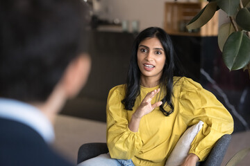 Focus on Indian professional woman engaged in conversation or discussion with client or teammate during meeting or negotiating, explain point, presenting idea, respond to question in coworking office