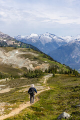 Fototapeta premium Hiker Exploring Scenic Alpine Trails with Snow-Capped Mountains in Whistler, BC, Canada
