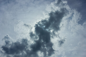 A dark grey storm cloud is backlit by the sun, creating a bright silver lining. Dramatic sky background