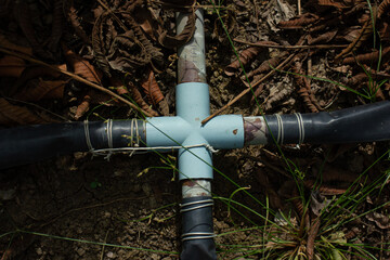 A PVC plastic garden irrigation pipeline system with ball valves, lying on the ground. Concept of gardening, agriculture, and DIY