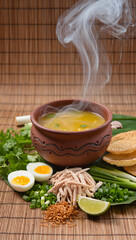 Soto ayam in traditional earthenware bowl on bamboo mat background, steam rising, surrounded by fresh ingredients