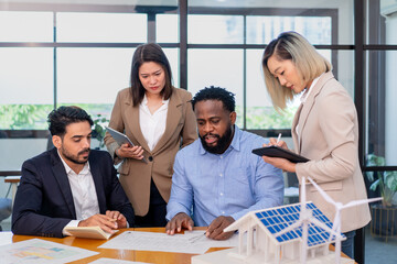 team of multiethnic coworker meeting on solar roof system project with solar panel house model, responsibility of green industry alternative renewable clean environment energy for sustainable business