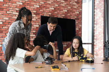 Teacher teaching diverse children training and learning robotics technology in classroom at school. Students training AI robot training kit and mechatronics in class