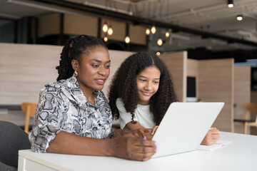 Female teacher teaching student using laptop computer in classroom. Student e-learning on laptop computer. Teacher assistance student using computer class in classroom