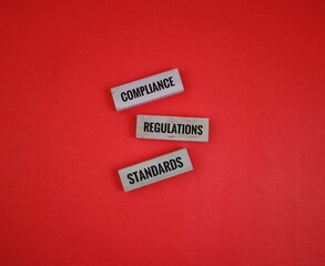 wooden blocks Displaying Compliance Regulations and Standards in Business Environment. isolated on a red background