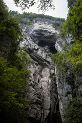 Obraz premium Majestic Rocky Cliff with Cave and Lush Foliage