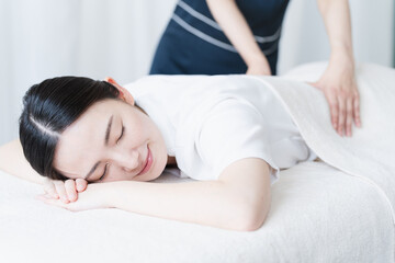 セラピストにマッサージを受ける若い女性　ビューティイメージ