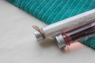 Two glass tubes filled with vibrant salt and spice are placed on a textured teal towel, showcasing their unique colors and inviting culinary possibilities.