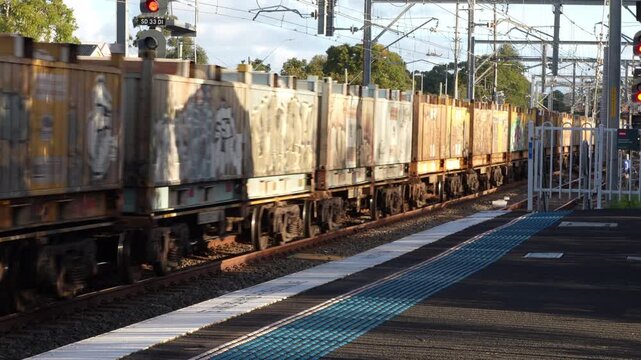 Freight Train Passing Through Railway Station at Speed &ndash; Industrial Cargo Transport in Motion