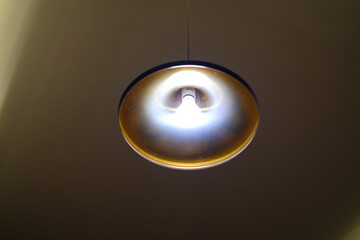 A light bulb hanging from the ceiling. The light is bright and the bulb is glowing