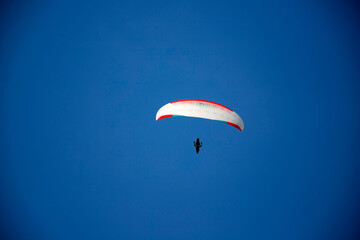 A man with a paraglider in front of a blue sky.