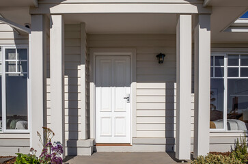 Front entrance of a modern suburban home in Australia, featuring horizontal weatherboard cladding,...