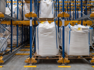 Large white bulk bags stored on pallets in industrial warehouse with multi-level racking system