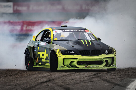 A high-performance racing car is captured in action on a racetrack, leaving a trail of smoke behind it as it speeds through the track