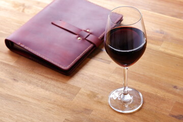 Red wine glass and notebook on table

