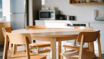 Fototapeta premium A light wooden dining table with matching chairs is set in a bright, modern kitchen, creating a welcoming space for meals.