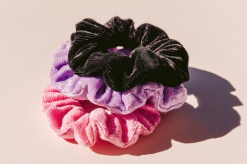 Three textured hair ties, stacked, in shades of purple, pink, and black