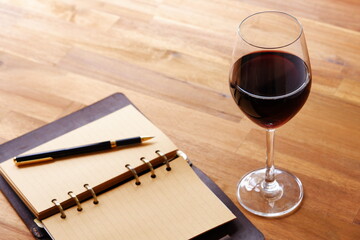 赤ワインを飲みながら、リング式のシステム手帳に日記をつけているイメージ写真
