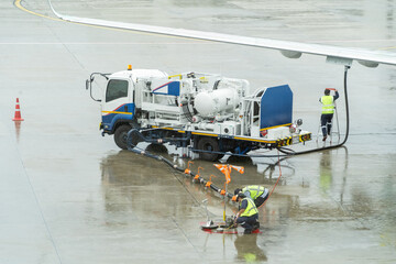 A man in a yellow vest is filling a plane with fuel