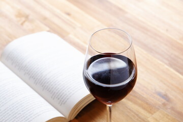 Glass of red wine with open book on table