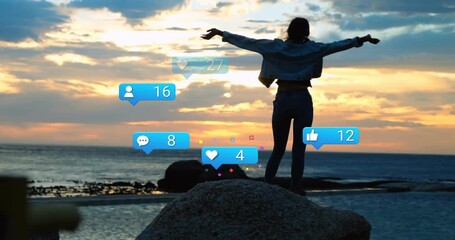 woman climbing rock at sunset holding phone watching social media icons rising celebrating feedback - Powered by Adobe