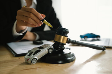 A lawyer uses a gavel near a toy car, symbolizing legal proceedings, car insurance claims, court...