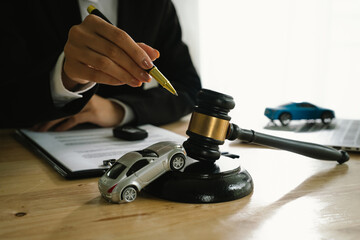 A lawyer uses a gavel near a toy car, symbolizing legal proceedings, car insurance claims, court...