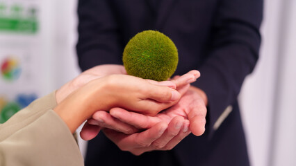 Business people hands exchanging green sphere symbolizing environmental sustainability partnership future growth global responsibility eco friendly solutions corporate initiative