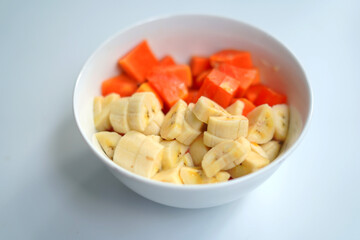 Sliced Papaya and Banana in White Bowl on White Background – Nutritious Fruit Mix.
