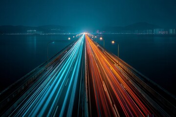 Obraz premium A long road with a bridge in the middle and a city in the background. The road is lit up with bright lights, creating a sense of movement and energy. The city in the background is lit up as well