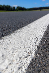 road during the day in sunny weather, paved road for vehicles with white road markings, close up